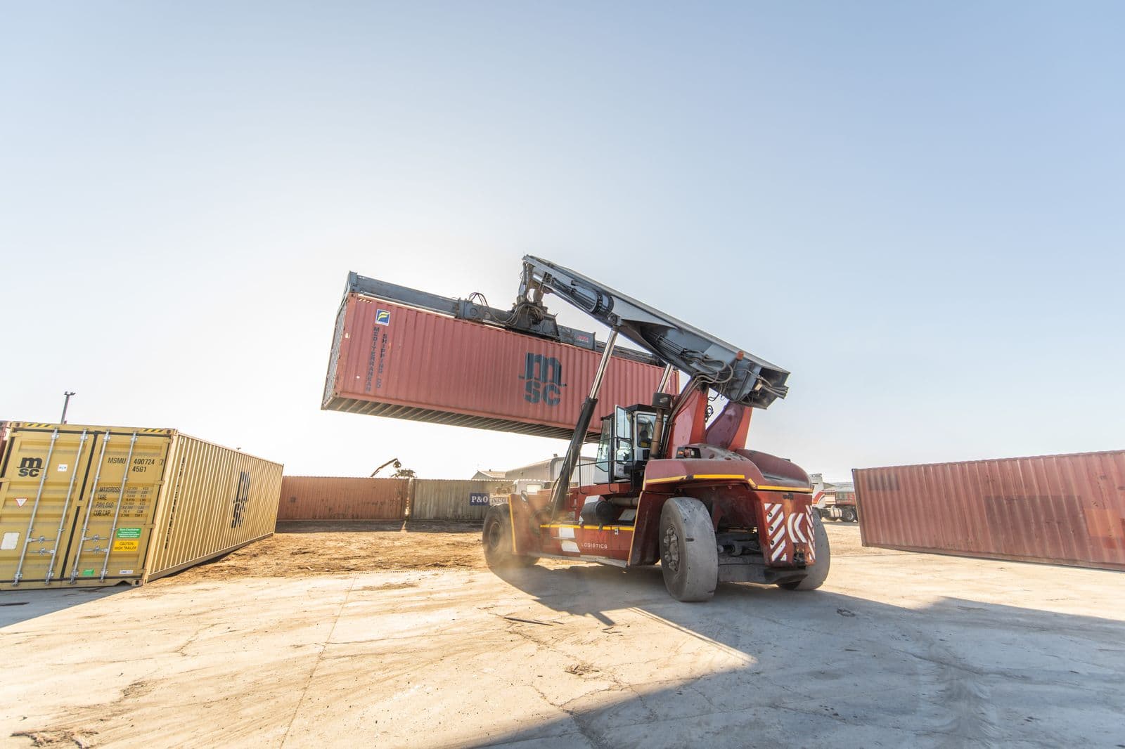 Reach stacker lifting a container against the sky