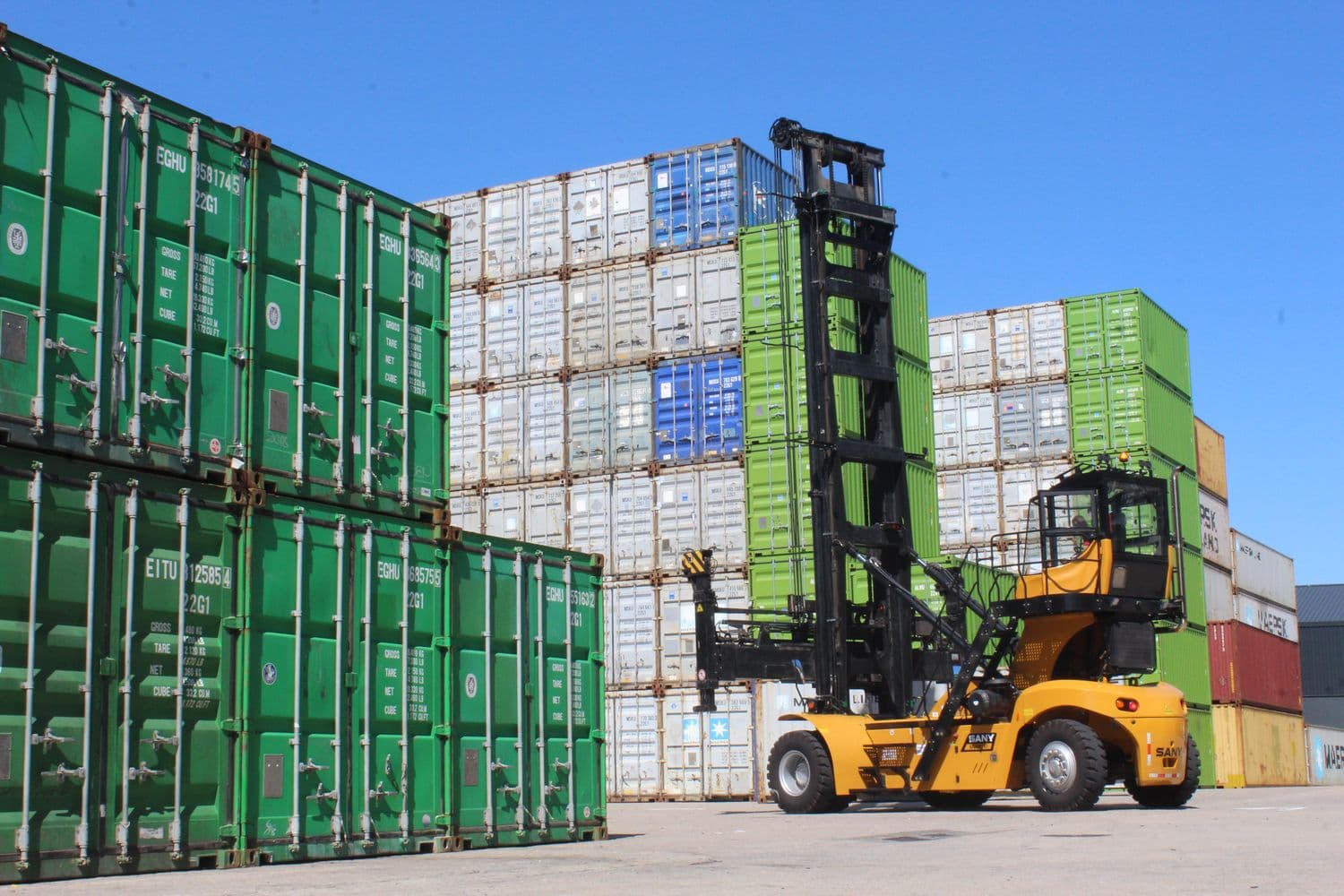 Reach stacker working green containers at the depot